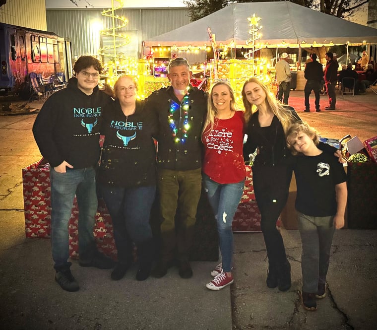 noble team and family together in front of  Christmas tree