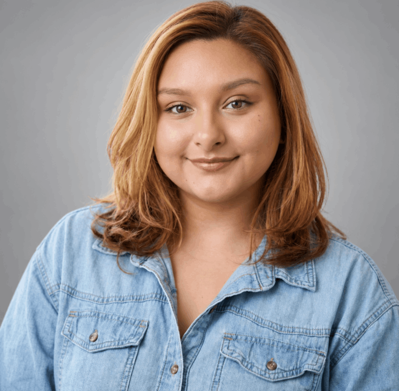 Sandra Perez smiling, wearing a light blue jean shirt, with a gray background